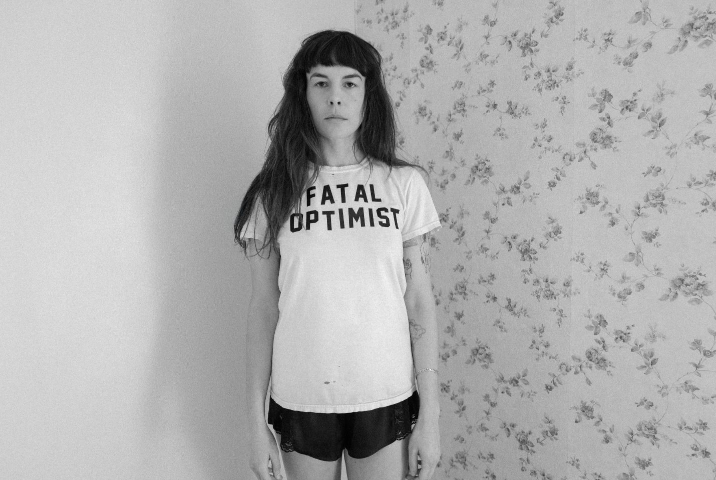A black & white image of a woman stood in the corner of a room